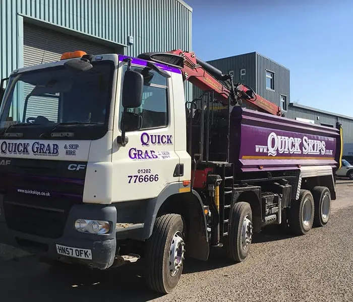 Quick Skips grab hire lorry loading waste on site in Castle Lane, Dorset